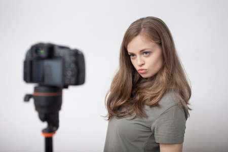 Smiling young caucasian girl woman making a video blog (vlog) with cameraの写真素材