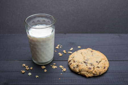 Oatmeal raisin cookie on black surface background, with glass of milkの写真素材