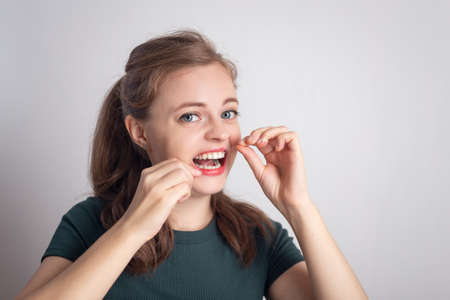 Funny smiling young caucasian woman girl using dental flossの写真素材