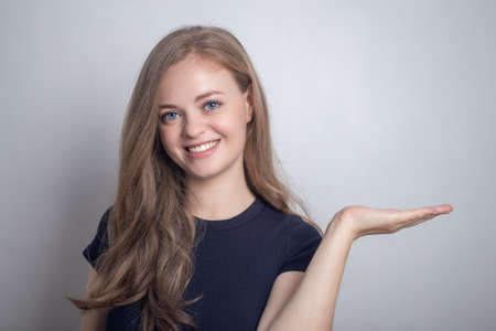 Smiling young caucasian girl woman showing pointing at white copy spaceの写真素材