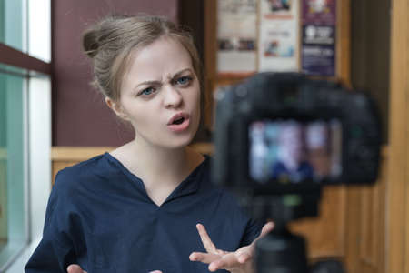 Smiling young caucasian girl woman making a video blog (vlog) with camera in a cafeの写真素材