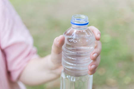 A hand holding a plastic bottle of water, close upの写真素材