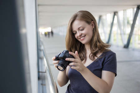Young caucasian woman girl photographer holding a digital camera in hands, taking a photo or videoの写真素材
