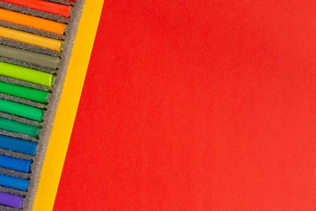 Colored pastel chalks on yellow red background. Flat lay, top view, copy space