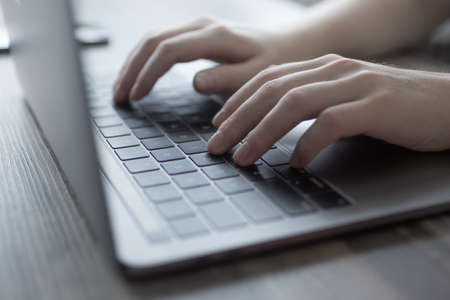 Hands typing on silver laptop computer keyboard, close upの写真素材