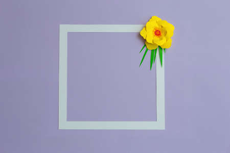 Square frame with yellow color paper flower on pastel violet blue background. Flat lay, copy spaceの写真素材