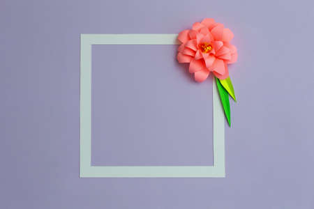 Square frame with pink color paper flower on pastel violet blue background. Flat lay, copy spaceの写真素材