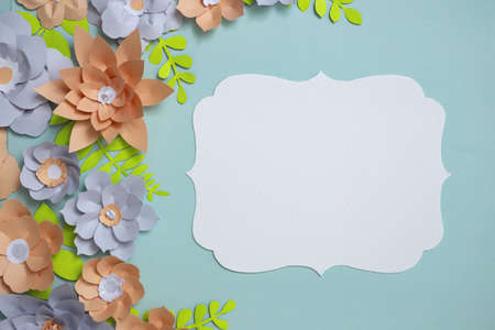Flat lay of vintage card frame, color paper flowers design on blue background. Top view, copy space,...