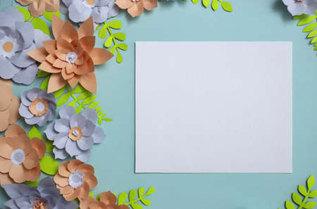 Flat lay of vintage square card frame, color paper flowers design on blue background. Top view, copy space, floral artの写真素材