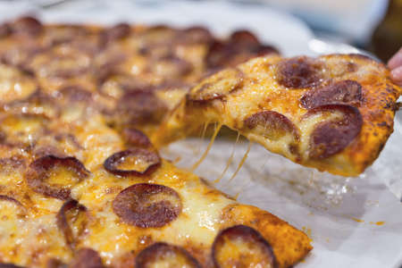 Close up texture of large cheesy pepperoni pizza, background macroの写真素材