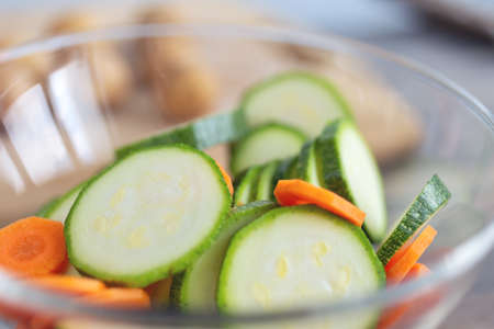 Close up of green zucchini cucumber and carrot slices in a bowl. Healthy food preparation conceptの写真素材