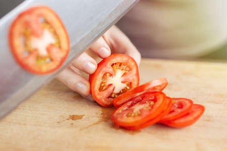 Close up of red ripe tomato cutting with a knife. Healthy food preparation conceptの写真素材
