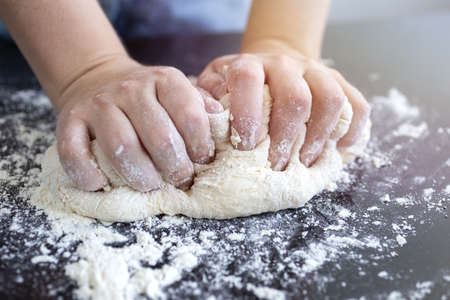 Close up of hands kneading dough for bread, pasta or pizzaの写真素材
