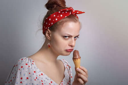 Frowning young Caucasian woman girl holding ice cream looks grumpy as if doesn't want to  share or angry, annoyedの写真素材