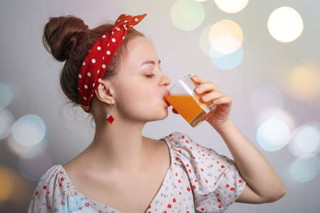 Young caucasian woman girl drinking a glass of orange or mango fruit juice or cocktail. Fresh summer party conceptの写真素材
