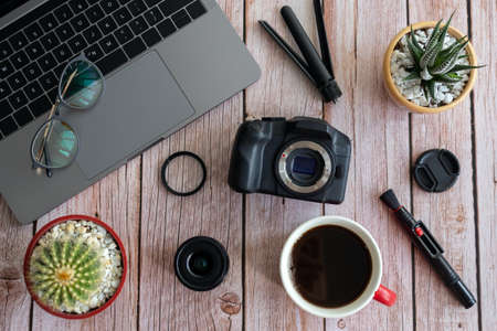Flat lay of photography equipment on wooden desktop background: dslr camera, laptop and lens. Blogger workspace concept. Top viewの写真素材