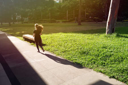 Makati, Manila, Philippines - May, 26, 2020: A girl is jogging in empty Ayala triangle park during coronavirus covid quarantine ECQ on a sunny dayのeditorial素材