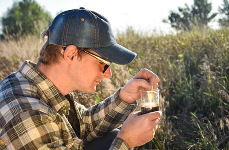 Close up male agronomy specialist testing soil sample outdoors, using laboratory equipment,...
