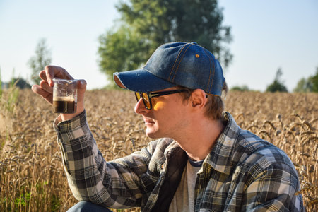 Male agronomy specialist testing soil sample outdoors, using laboratory equipment, performing soil...