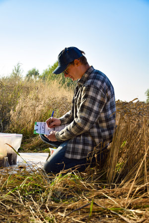 Male agronomist preparing soil samples for laboratory analysis, writing in information sheet...
