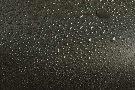 Water droplets on black background. Textured surface. Studio shot. Close-up view