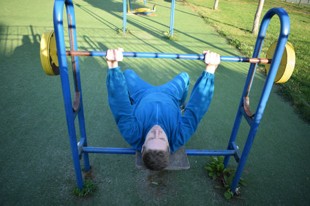 A dedicated young athlete puts in the hard work, vigorously training on gym equipment outdoors to...