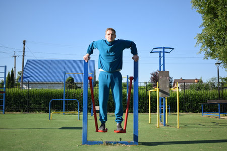 A dedicated young athlete puts in the hard work, vigorously training on gym equipment outdoors to...