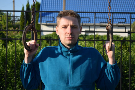 A dedicated young athlete puts in the hard work, vigorously training on gym equipment outdoors to...