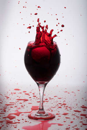 Red wine splashing out from a glassの写真素材