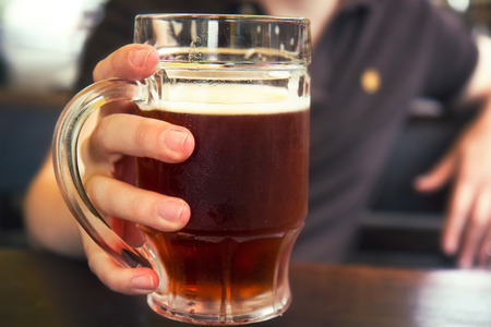 Dark beer in mans hand,mug of beer,の写真素材