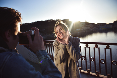 A man make a portrait of happy smiling woman standing on the bridge on sunny summer or spring day outdoorの写真素材