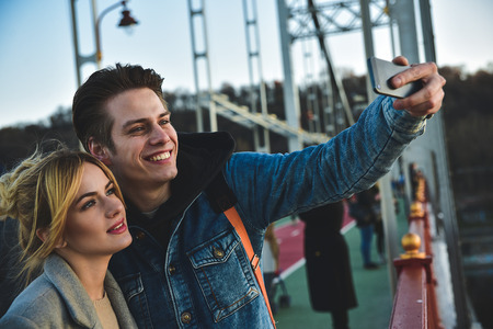 Happy couple make a photo on the phone standing on the bridge.の写真素材