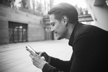Smiling businessman use a smartphone at street.の写真素材