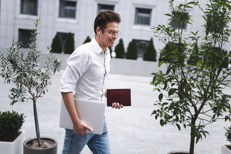 Portrait of young handsome guy with headphones and glasses in modern city.の写真素材