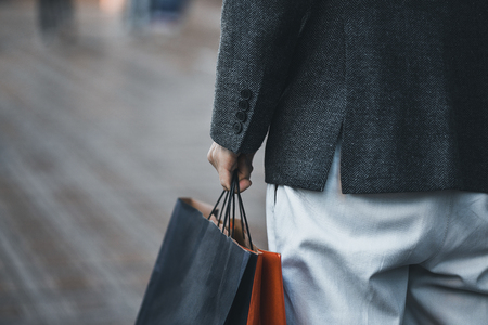 Close up of a young caucasian man holding some different paper shopping bags in the street.の写真素材