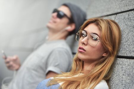 Portrait of Young attractive couple listening to music on the same pair of headphones, dressed in...