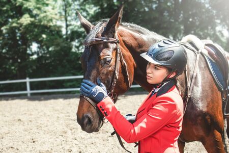 A young girl talking and takes care of her horse. She loves the animals and joyfully spends her time in their environment.の写真素材