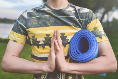 Yoga. Close up men hands. Young men do yoga outdoors on mat.Guy exercising yoga on the garden.Young men meditating in lotus posture closeup. zen