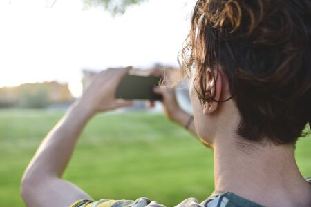 close-up guy takes pictures of nature, beautiful views on his smartphone. summer moodの写真素材