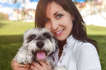 Portrait of a happy caucasian woman who hugs her beloved dog.The concept of love for animals. best friends. Dog breed Schnauzer. sunny dayの写真素材