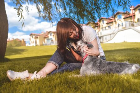 Caucasian joyful woman playing with her beloved dog in the park. The concept of love for animals....