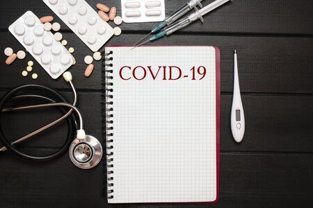 Coronavirus. COVID-19, Medical Tools, Syringe and Colorful Drugs and Capsules Medicine Concept, Brown Wood Background, Front View, Close Up, Isolatedの写真素材
