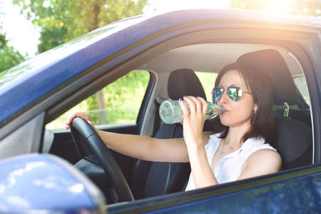Beautiful adult happy woman driving her car in summer day
