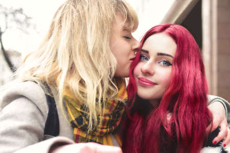 blonde Lesbian kissing forehead of her loving girlfriend with pink hair, gentle attitude, first love. lesbian couple. best friendsの写真素材