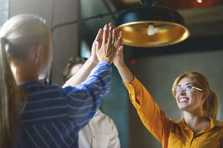 Close up top view of young business people putting their hands together. Stack of hands. Unity and...