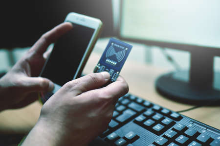 Male hacker is trying to access the phone. Security and protection of personal data. The concept of cyber crime and hacking electronic devicesの写真素材