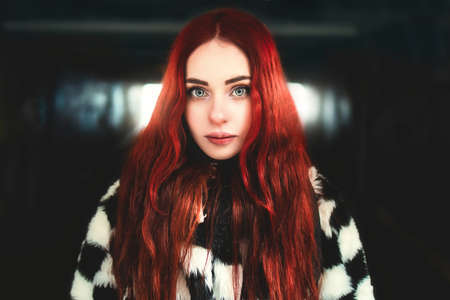 Portrait of a beautiful woman with red hair standing in the underground passageの写真素材
