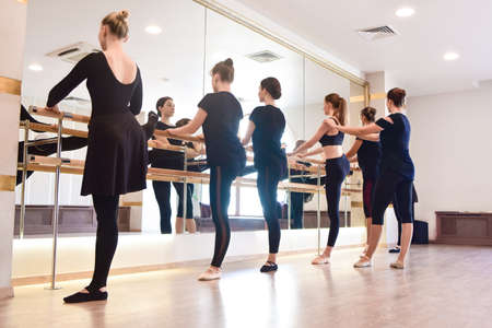 Side view Groups of Girls performing exercises on the bar at the gym with a focus on athleticism in...