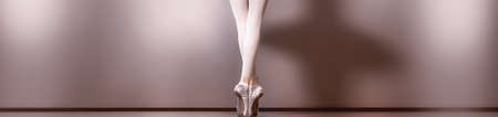 a panoramic view from the back of the beautiful legs and feet on tiptoes dressed in pointe shoes of a young ballerinaの写真素材