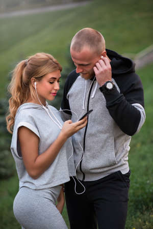 Caucasian sportive couple dating on after training, listening to music, having fun together. Sports and Outdoor Activities, Technology and People Relations Conceptの写真素材